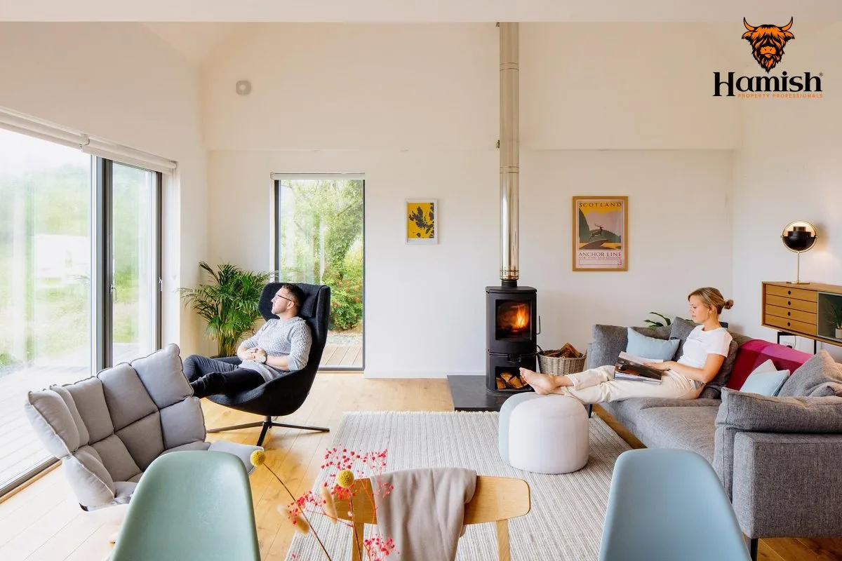 People viewing a bright Highland home with large windows and a wood-burning stove